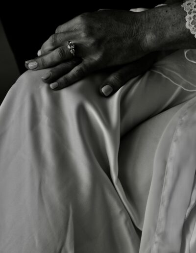 Black and white close-up of a bride's hand with an engagement ring resting on a satin robe